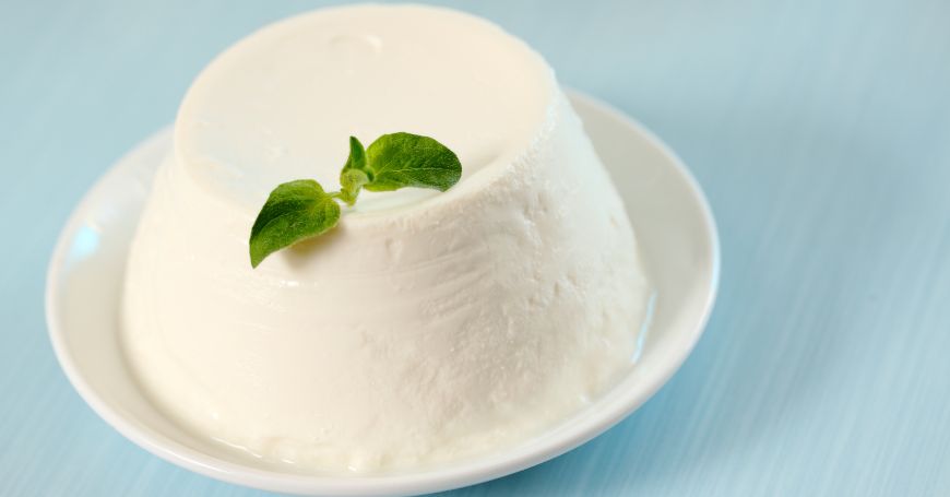 Ricotta fresca su piatto bianco: alimento digeribile per chi soffre di colite e colon irritabile, ma da consumare con attenzione