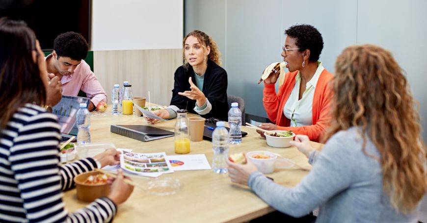 Team aziendale che condivide un pasto sano, strategia utile per gestire la colite al lavoro