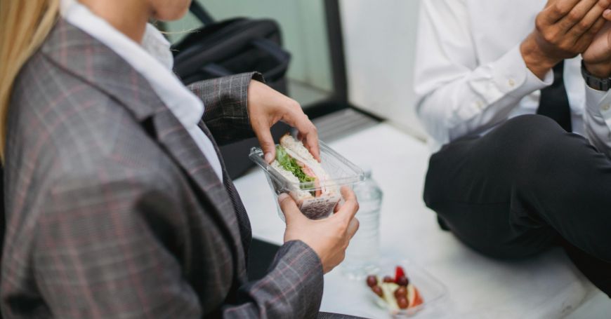 Professionista in giacca mangia un pasto leggero preparato da casa per gestire la colite al lavoro