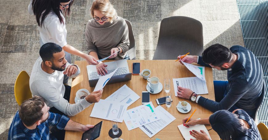 Riunione strategica tra colleghi mentre uno dei partecipanti affronta la colite al lavoro con discrezione