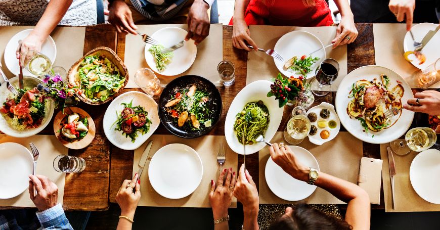Tavolata conviviale con piatti semplici e vari, scelta ideale per mangiare fuori casa con la colite
